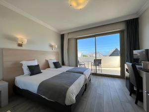 a hotel room with a bed and a large window at Hôtel Ker-Noyal Quiberon Plage in Quiberon