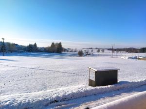 un campo cubierto de nieve con un cubo de basura. en Apartmán Restaurace 16, 