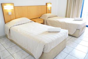 - 2 lits dans une chambre d'hôtel avec des draps blancs dans l'établissement Green Bungalows Hotel Apartments, à Ayia Napa
