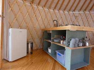a kitchen with a refrigerator and shelves in a room at modern Mongolian yurt in Grohoţele