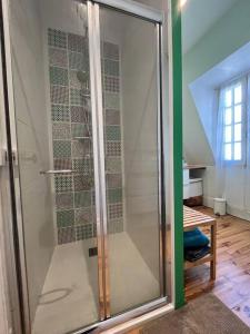 La salle de bains est pourvue d'une douche avec une porte en verre. dans l'établissement Maison de caractère en centre ville, à Vichy