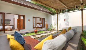 uma sala de estar exterior com um sofá e cadeiras em KU Villas em Kuta Lombok