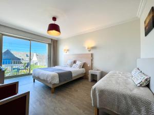 a bedroom with two beds and a large window at Hôtel Ker-Noyal Quiberon Plage in Quiberon