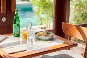 uma mesa com uma tigela de comida e uma garrafa de cerveja em KU Villas em Kuta Lombok