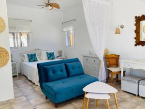 a bedroom with a bed and a blue couch at La Rústica en Viñuela, piscina privada in Viñuela