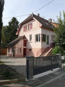 une maison rose avec une clôture devant elle dans l'établissement Le logis du mineur Chez Agnès et Joël, à Staffelfelden