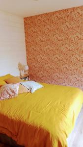 une chambre avec un lit jaune et un mur dans l'établissement Le cottage du Marais., à Houlle