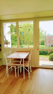 une salle à manger avec une table et deux fenêtres dans l'établissement Le cottage du Marais., à Houlle 10 autres photos