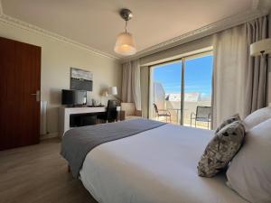 a hotel room with a large bed and a large window at Hôtel Ker-Noyal Quiberon Plage in Quiberon