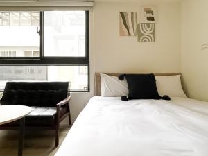 a bedroom with a bed and a chair and a window at 旅行家 Affetto Hostel in Taichung