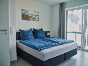 Schlafzimmer mit einem Bett mit blauer Bettwäsche und einem Fenster in der Unterkunft Ferienbude an den Wehlen in Büsum
