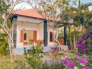 a house in the middle of a garden with flowers at Orange Balangan Bungalow in Uluwatu