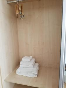 una pila de toallas sentadas en un estante en un baño en London Luxury Apartments 1 min from Redbridge Station with Parking, en Wanstead