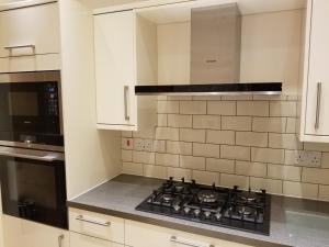 cocina con fogones y microondas en London Luxury Apartments 1 min from Redbridge Station with Parking, en Wanstead