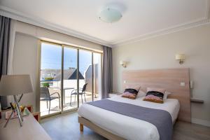 a bedroom with a large bed and a balcony at Hôtel Ker-Noyal Quiberon Plage in Quiberon