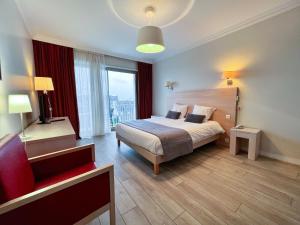 a hotel room with a bed and a red chair at Hôtel Ker-Noyal Quiberon Plage in Quiberon
