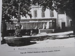 czarno-białe zdjęcie budynku z fontanną w obiekcie Hôtel Moderne Veynes -Appart Hôtel- w mieście Veynes
