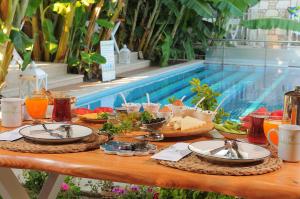a table with plates of food next to a pool at Giritlim Otel in Çeşme