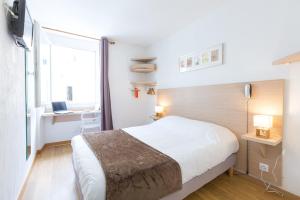 a bedroom with a bed and a desk and a window at Europe Hotel Vieux Port in Marseille