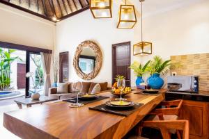 a dining room with a large wooden table with chairs at Villa Joyosa in Seminyak