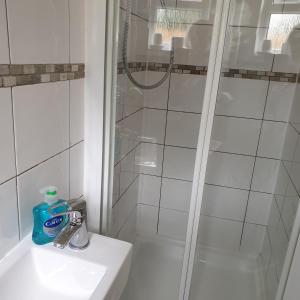 baño blanco con ducha y lavamanos en Beachfront Studio en Pevensey