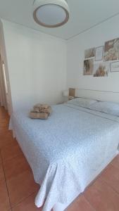 a white bedroom with a bed with a blue blanket at MET&GOLF OLIVA NOVA BEACH JARDIN in Oliva