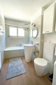 a bathroom with a toilet and a tub and a sink at Traumhafte Sonnenresidenz mit Berg- und Seeblick in Amden