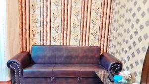 Hotel Super Seven في لاهور: أريكة جلدية بنية الجلوس في غرفة مع طاولة زجاجية