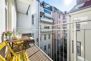 a balcony with a wooden table and yellow chairs at A&S Center Apartment Vienna in Vienna