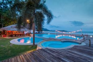 a swimming pool next to the ocean at night at Twin Bay Resort - SHA Extra Plus in Ko Lanta