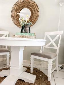 a white dining room table with two chairs and a mirror at Knot a Care Remodeled Direct water access condo with ocean and pool views NOW SLEEPS SIX in Marco Island