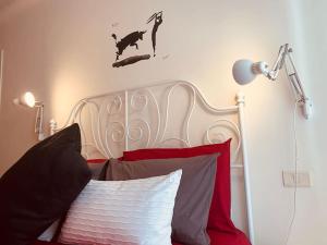 a bed with a white headboard and red pillows at Maison de Maff in Pesaro