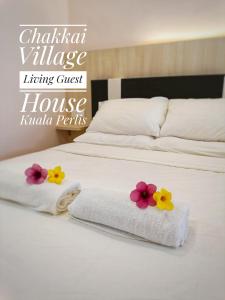 two beds with towels and flowers on top of them at Chakkai Village Living Guest House in Kuala Perlis