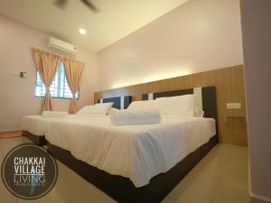 een slaapkamer met een groot bed met witte lakens bij Chakkai Village Living Guest House in Kuala Perlis