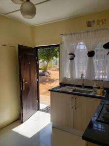 een keuken met een wastafel en een deur naar een tuin bij Kasuda three bedrooms house in Livingstone in Livingstone