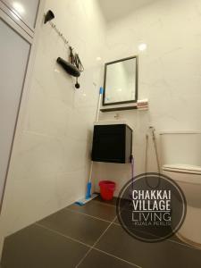 a bathroom with a tv and a mirror on the wall at Chakkai Village Living Guest House in Kuala Perlis