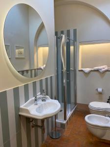 ein Badezimmer mit einem Waschbecken, einem WC und einem Spiegel in der Unterkunft Relais Maria Cristina in Chianni