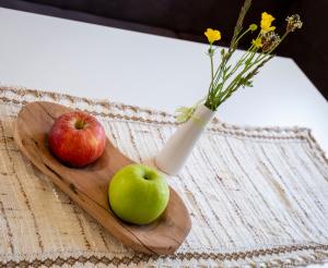 deux pommes sur une planche de découpe avec un vase avec des fleurs dans l'établissement Moarhof in Oberbozen, à Soprabolzano