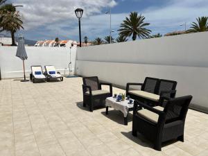 a patio with chairs and a table and a white wall at Lovely Home Casa Tamaide - Costa del Silencio - in Costa Del Silencio