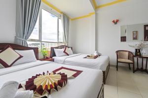 ダラットにあるMiền Nhiệt Đới 2 Hotelのベッドが2つと窓があるホテルの部屋