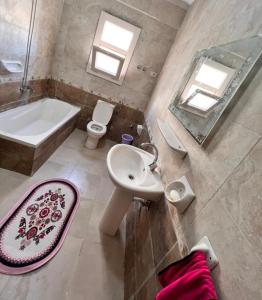 a bathroom with a sink and a tub and a toilet at Coral hills North Coast كورال هيلز الساحل الشمالي in El Dab‘a