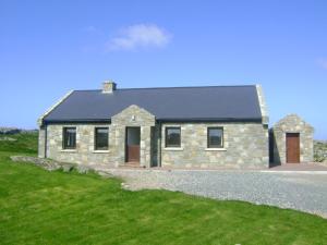 a stone house on the side of a road at Luxury Sea View Cottage Ballyconneely Winter Specials in Ballyconneely