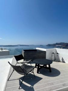 eine Terrasse mit einem Tisch und Stühlen auf dem Dach in der Unterkunft ArmonOia Suites in Oia