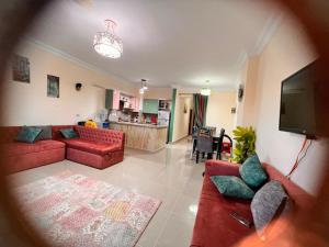 a living room with red couches and a flat screen tv at Coral hills North Coast كورال هيلز الساحل الشمالي in Zāwiyat al ‘Awwāmah