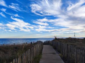 um caminho de madeira que leva à praia com um céu nublado em L'OSTRA de l'impasse em Portiragnes