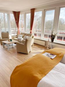 a living room with a bed and chairs and windows at Ringhotel Hohe Wacht in Hohwacht