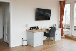 a room with a desk with a chair and a tv on the wall at Ringhotel Hohe Wacht in Hohwacht