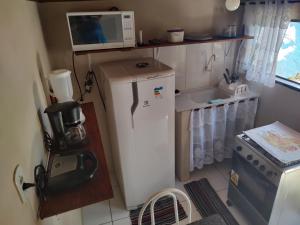 a small kitchen with a refrigerator and a microwave at Hospedagem capitão Hula in Abraão