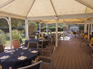 a pavilion with tables and chairs with blue tables and chairs at Hotel La Buca Del Gatto in Marina di Cecina