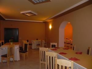 ein Esszimmer mit Tischen, Stühlen und einem Torbogen in der Unterkunft Motel Fogado in Cristuru Secuiesc